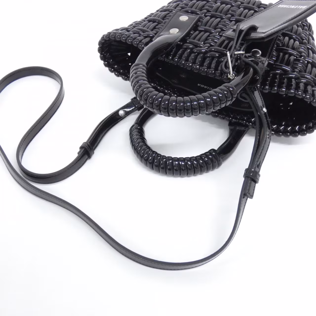 Small woven basket-style bag with a top handle and front logo detail.