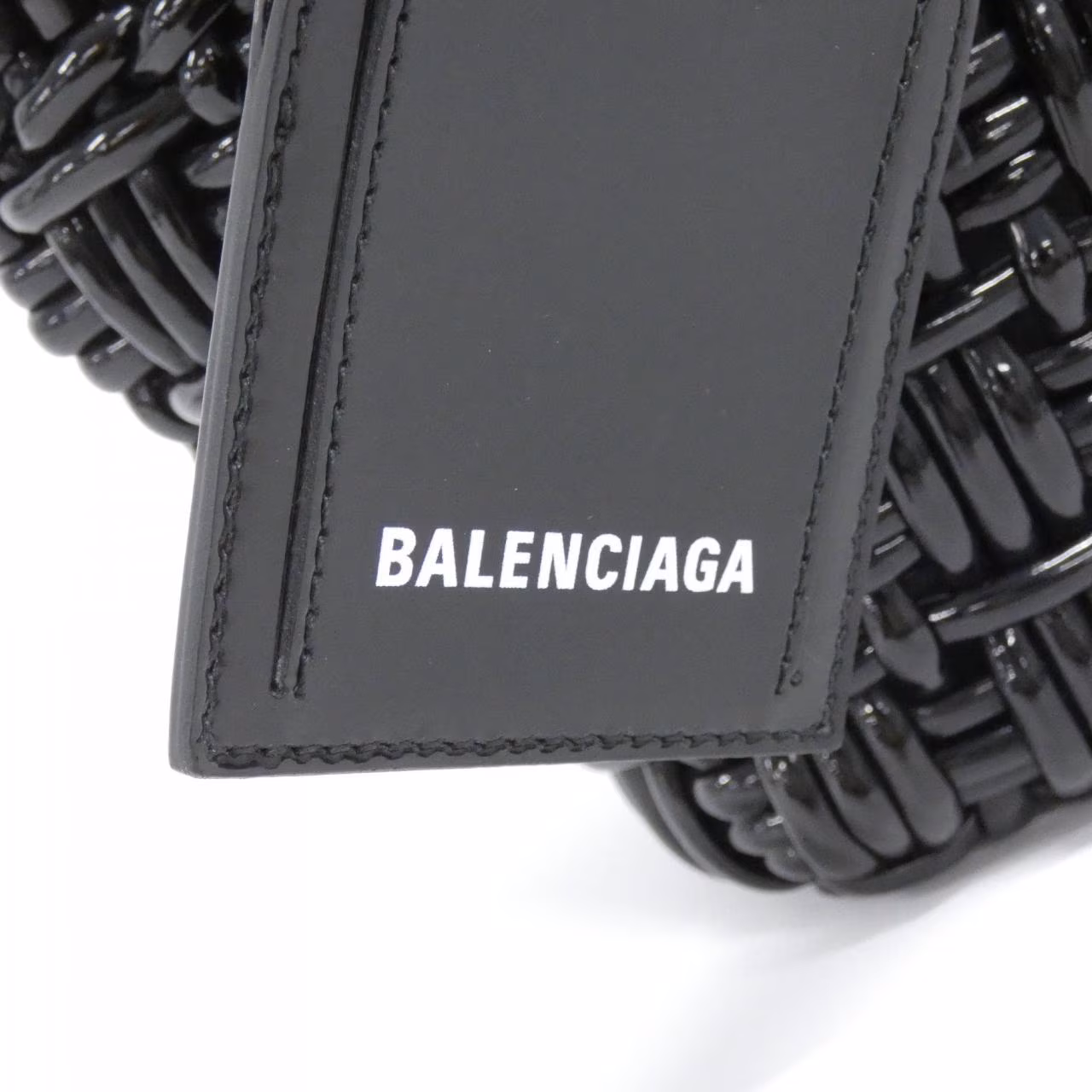 Small woven basket-style bag with a top handle and front logo detail.