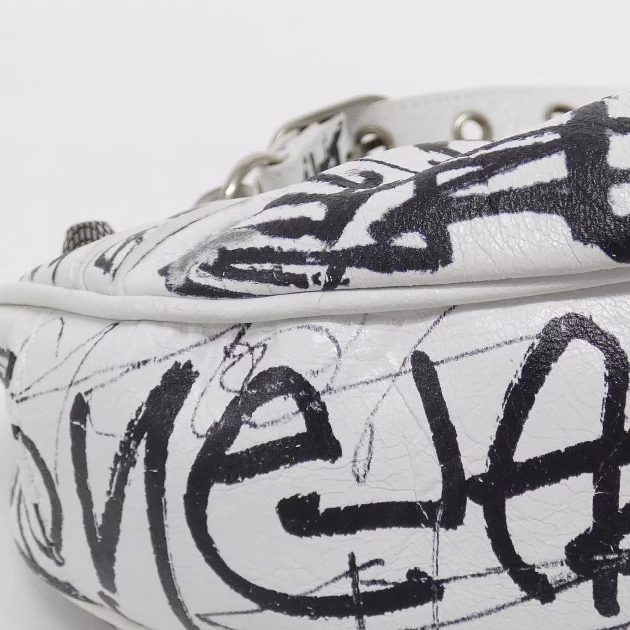 Slouchy shoulder bag with studded hardware, buckle strap and graffiti-style printing.