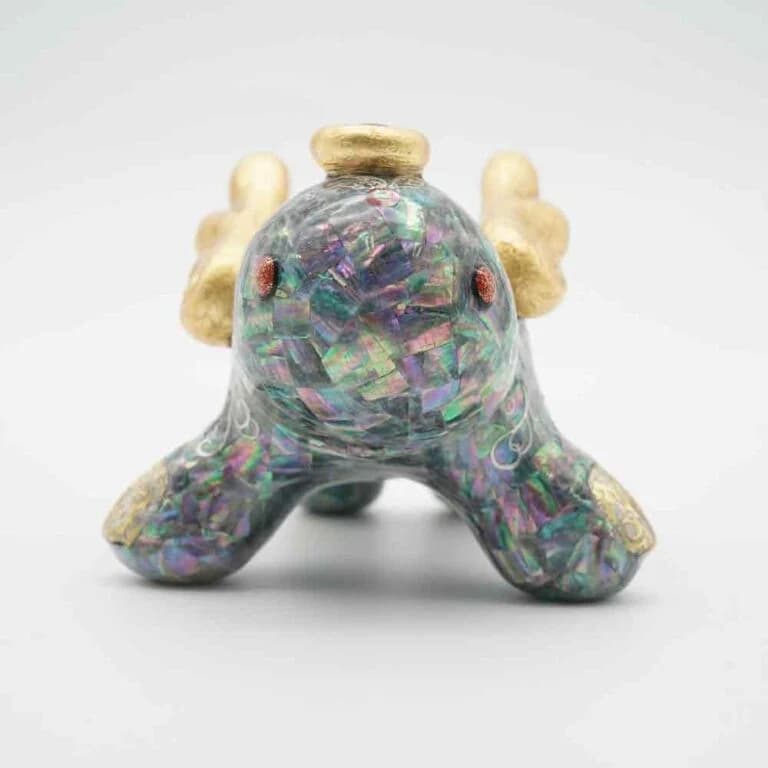 Small soft vinyl figure with iridescent shell inlay detailing across its surface.