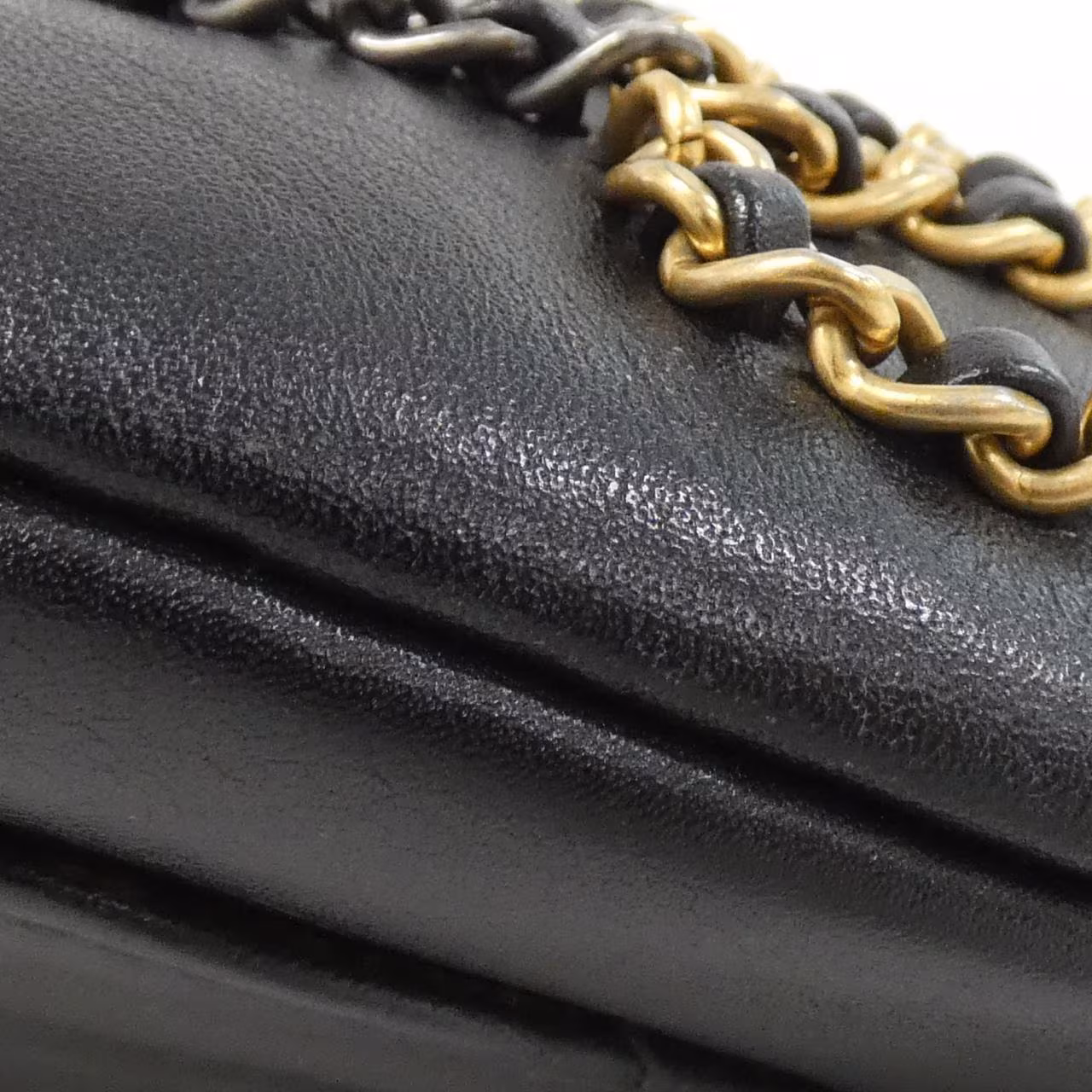 Small black quilted belt bag with a chain and leather strap.