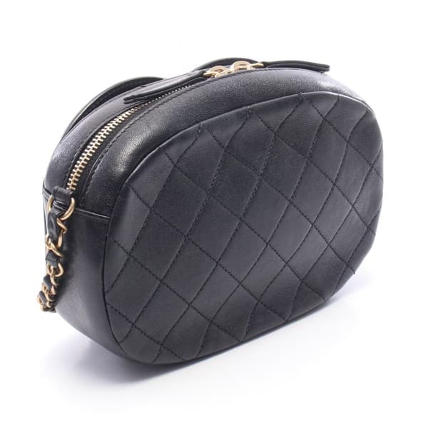 Black quilted leather camera bag with gold-tone logo clasp and a shoulder strap.