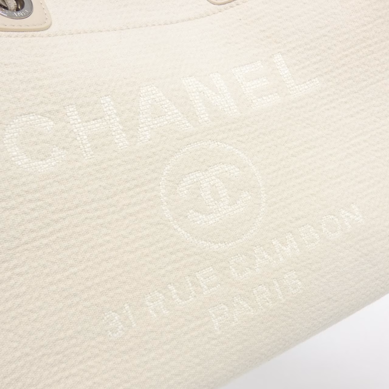 Tote bag with woven handles and a large logo on the front.