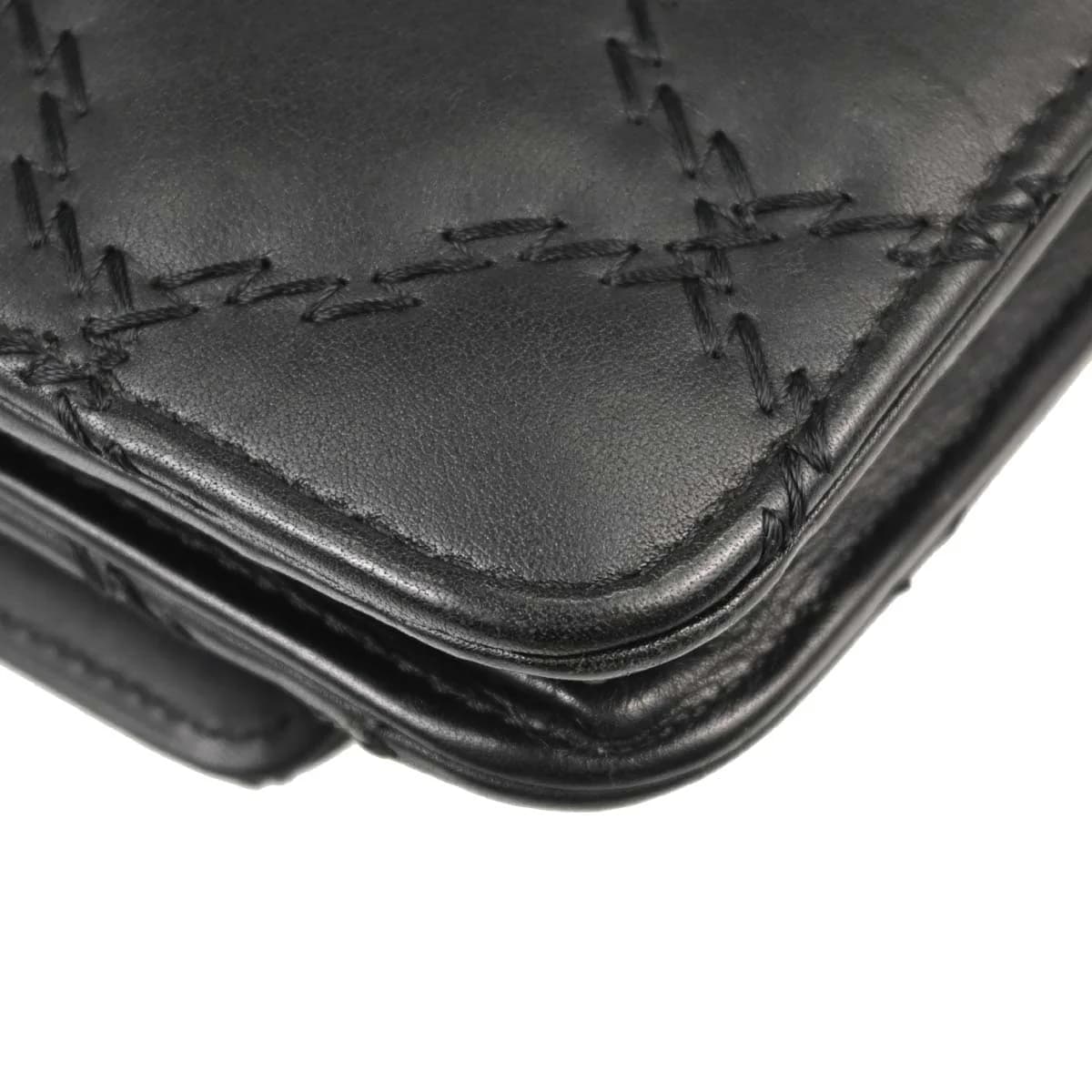 Small black leather flap bag on a chain strap, quilted front with turnlock closure.