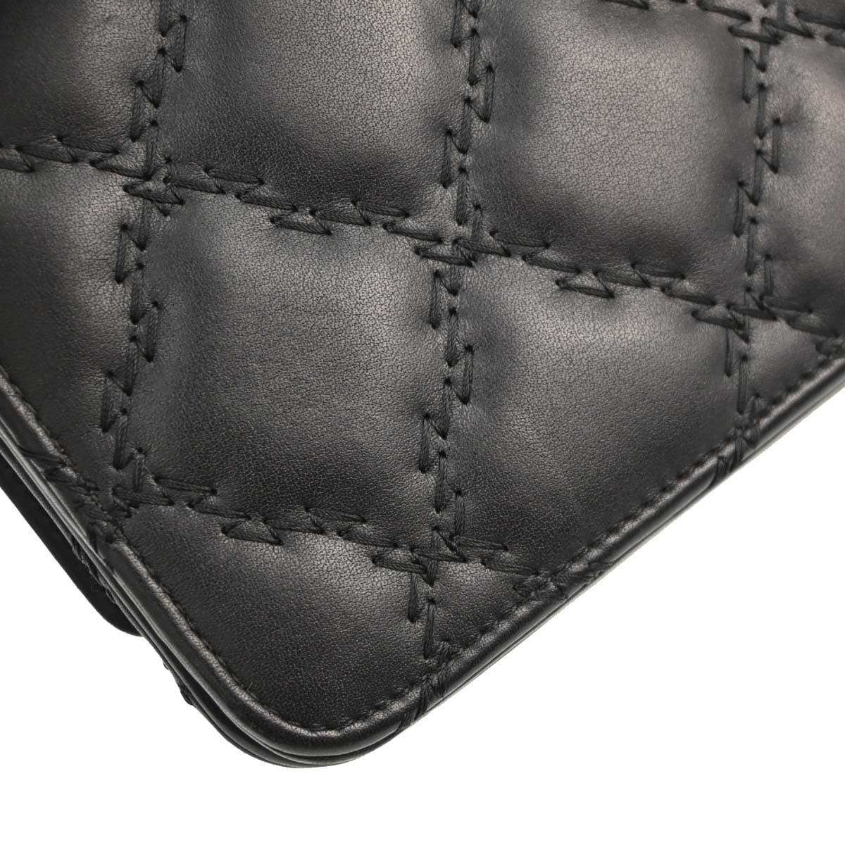 Small black leather flap bag on a chain strap, quilted front with turnlock closure.
