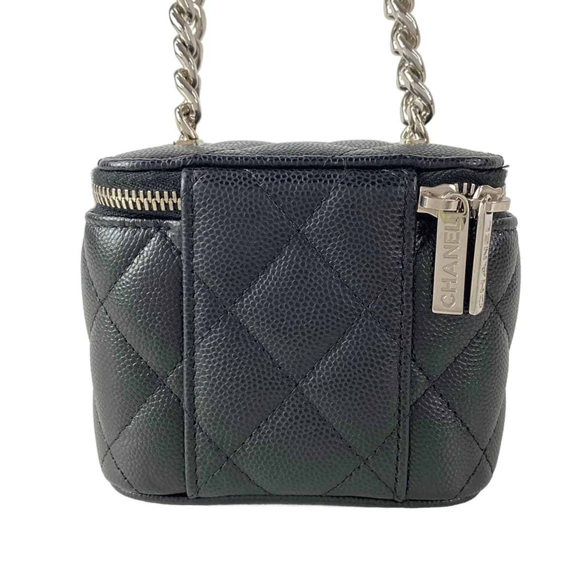 Small black quilted boxy bag with a top handle and chain strap.