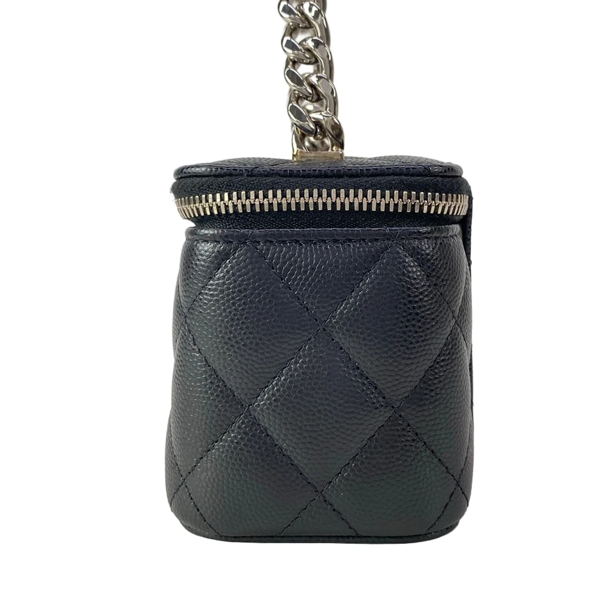 Small black quilted boxy bag with a top handle and chain strap.