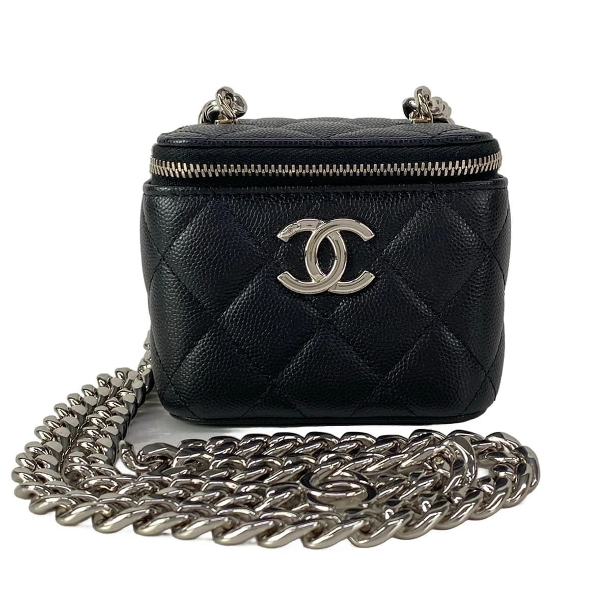Small black quilted boxy bag with a top handle and chain strap.