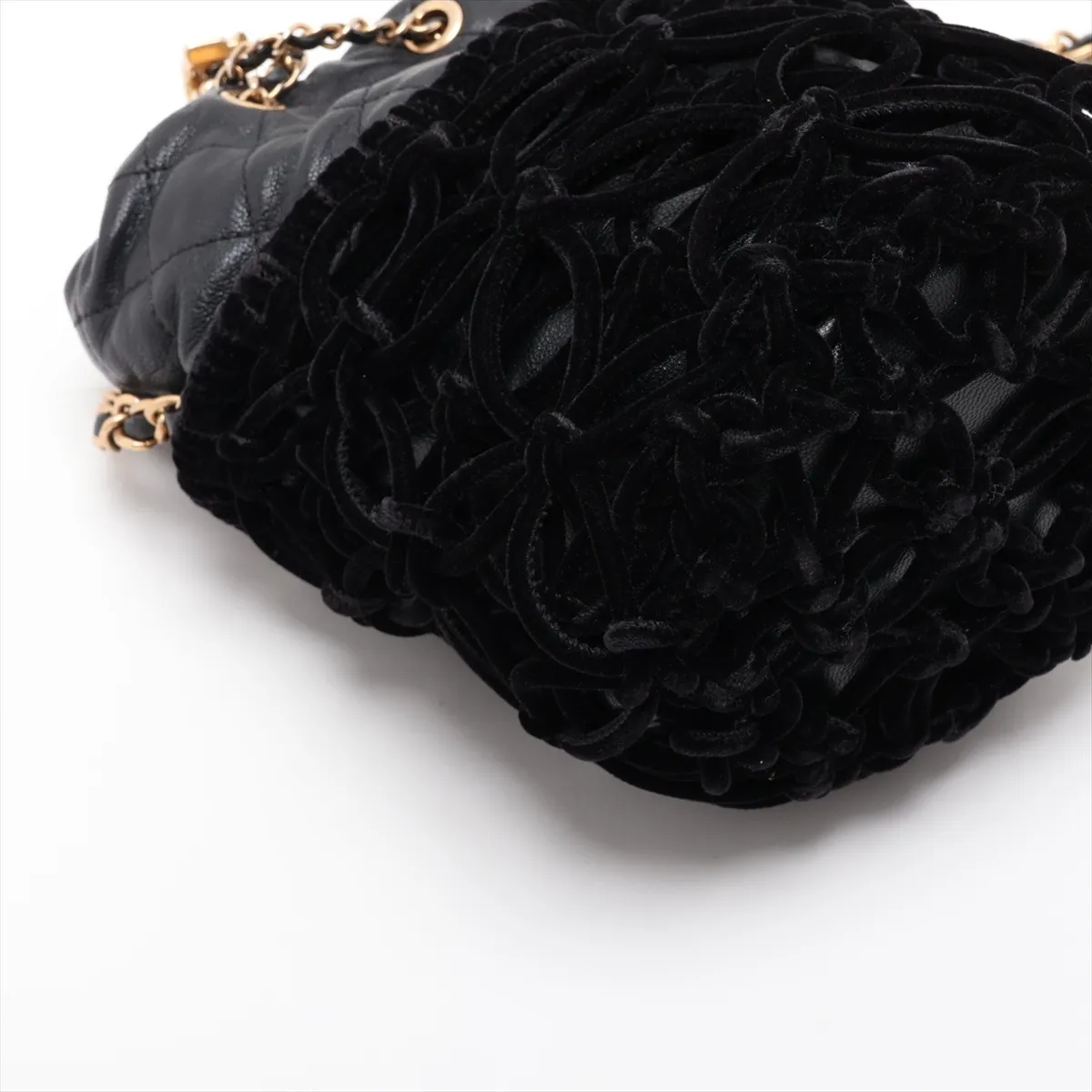 Black quilted drawstring bag with a gold chain strap and soft velour panels.