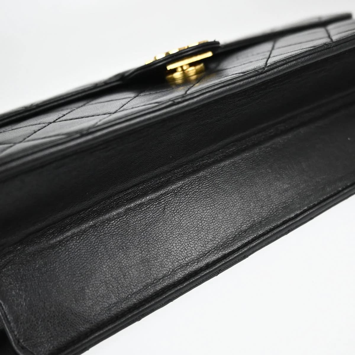 Black quilted leather flap bag with chain shoulder strap and square turnlock on the flap