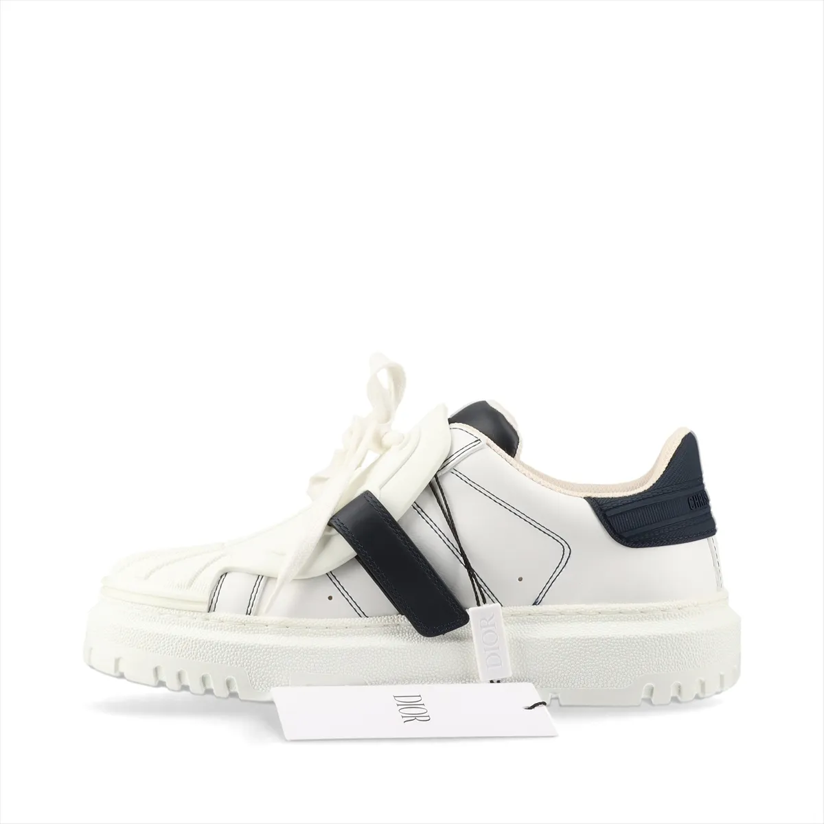 Pair of low-top sneakers in white with navy panels, chunky white sole, photographed on a plain background