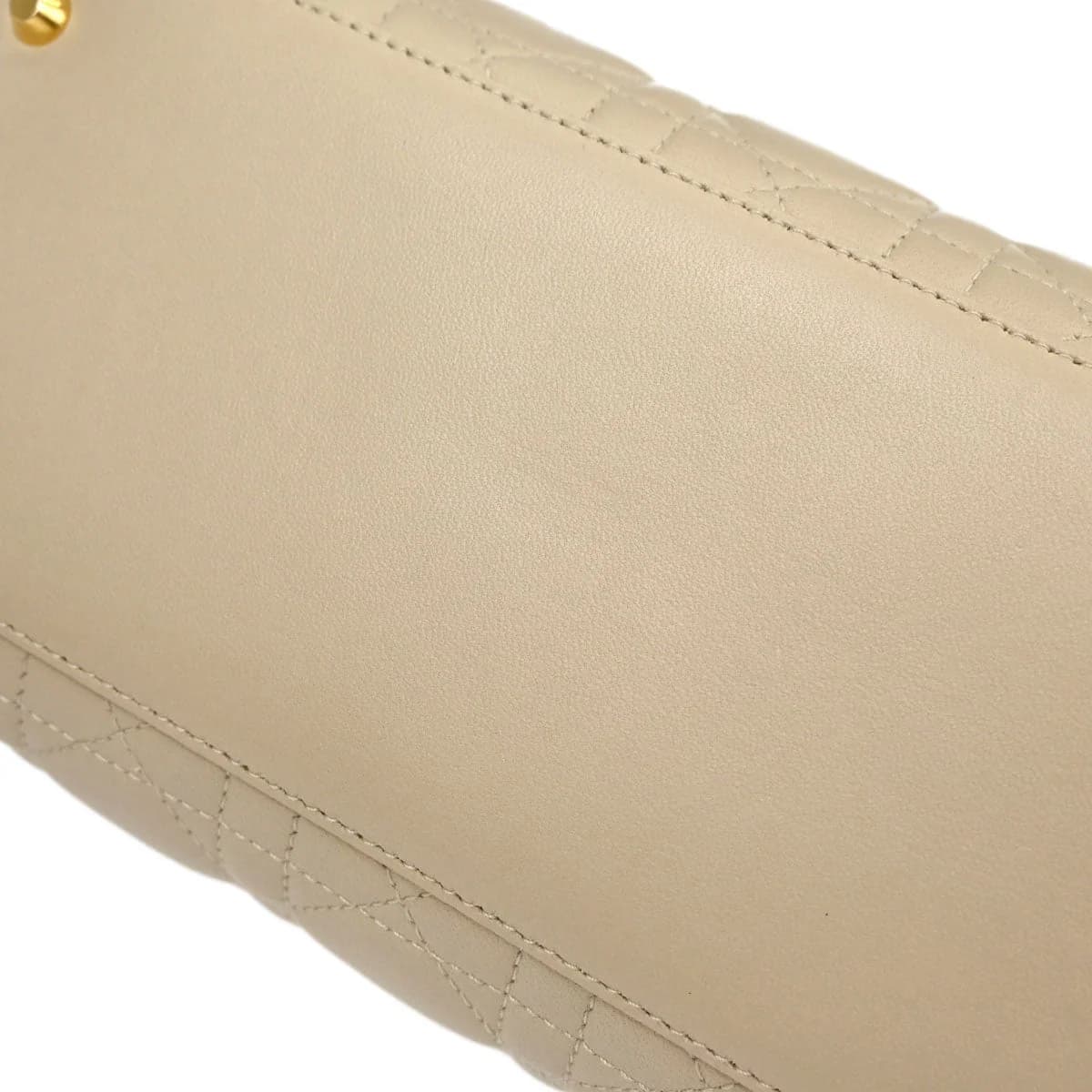 Beige quilted lambskin bag with top handles and hanging charms.