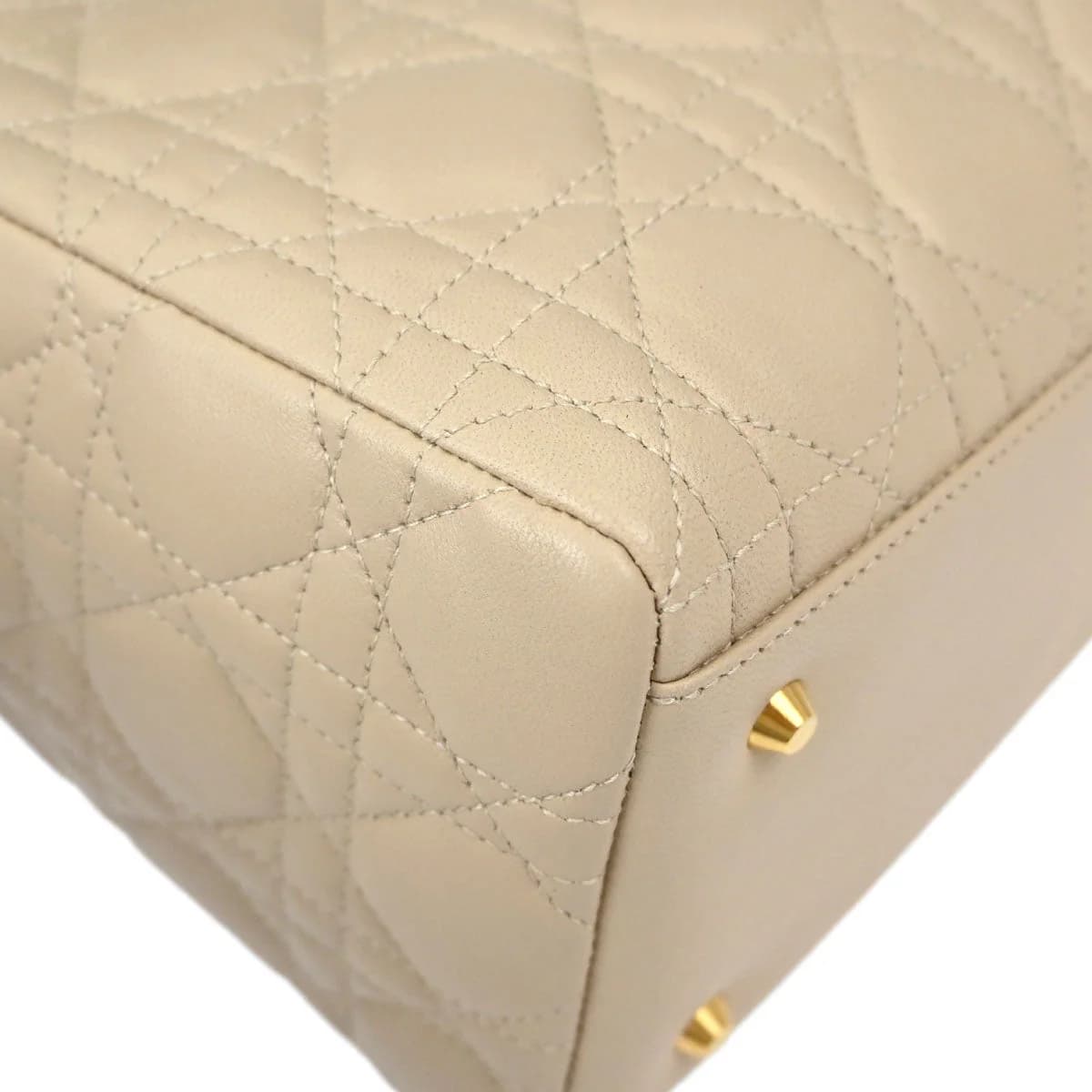Beige quilted lambskin bag with top handles and hanging charms.
