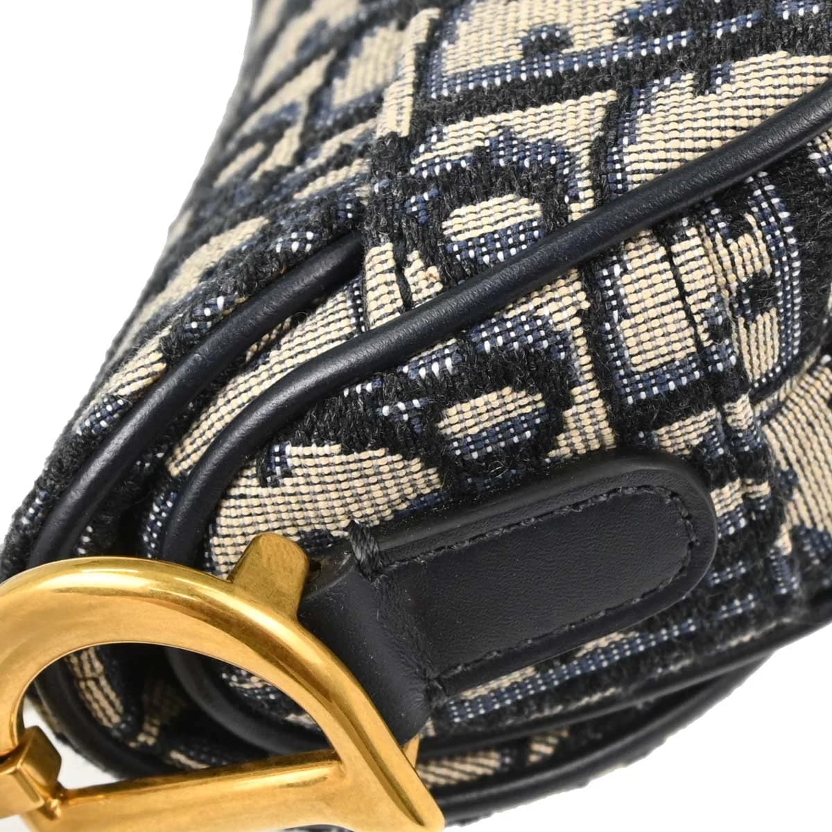 Curved saddle-shaped bag in navy patterned canvas with beige trim and a strap.