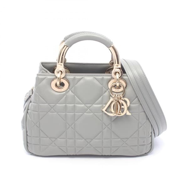 Grey quilted leather handbag with a top handle and rounded flap body.