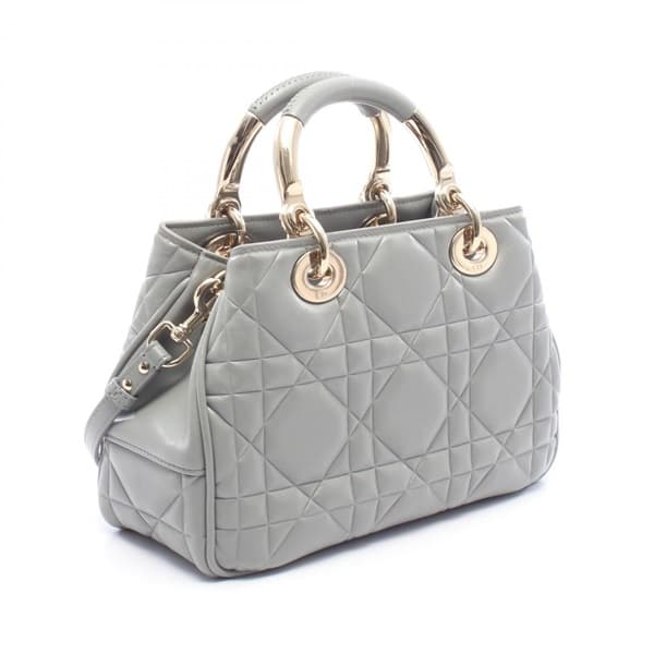 Grey quilted leather handbag with a top handle and rounded flap body.