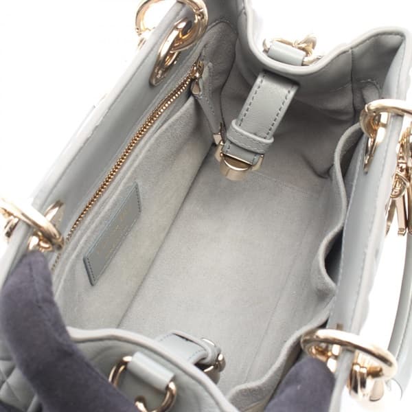 Grey quilted leather handbag with a top handle and rounded flap body.