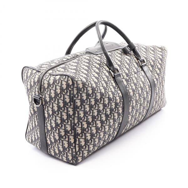 Navy and beige patterned canvas duffle bag with leather handles and trim.