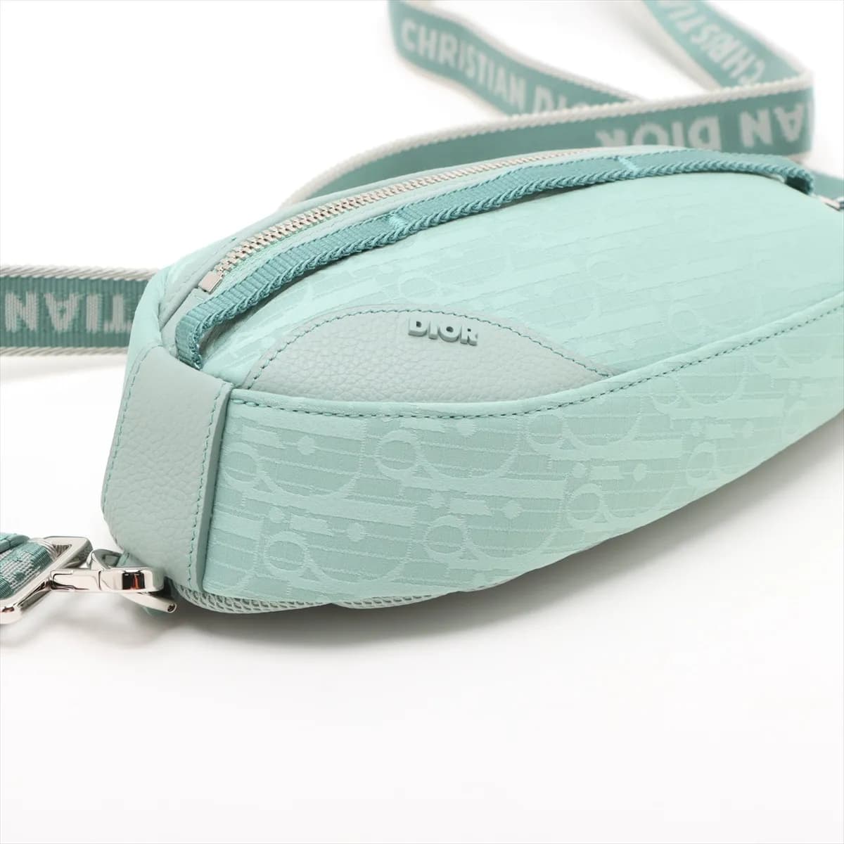 Green patterned nylon body bag with dark leather trim and a wide adjustable strap.