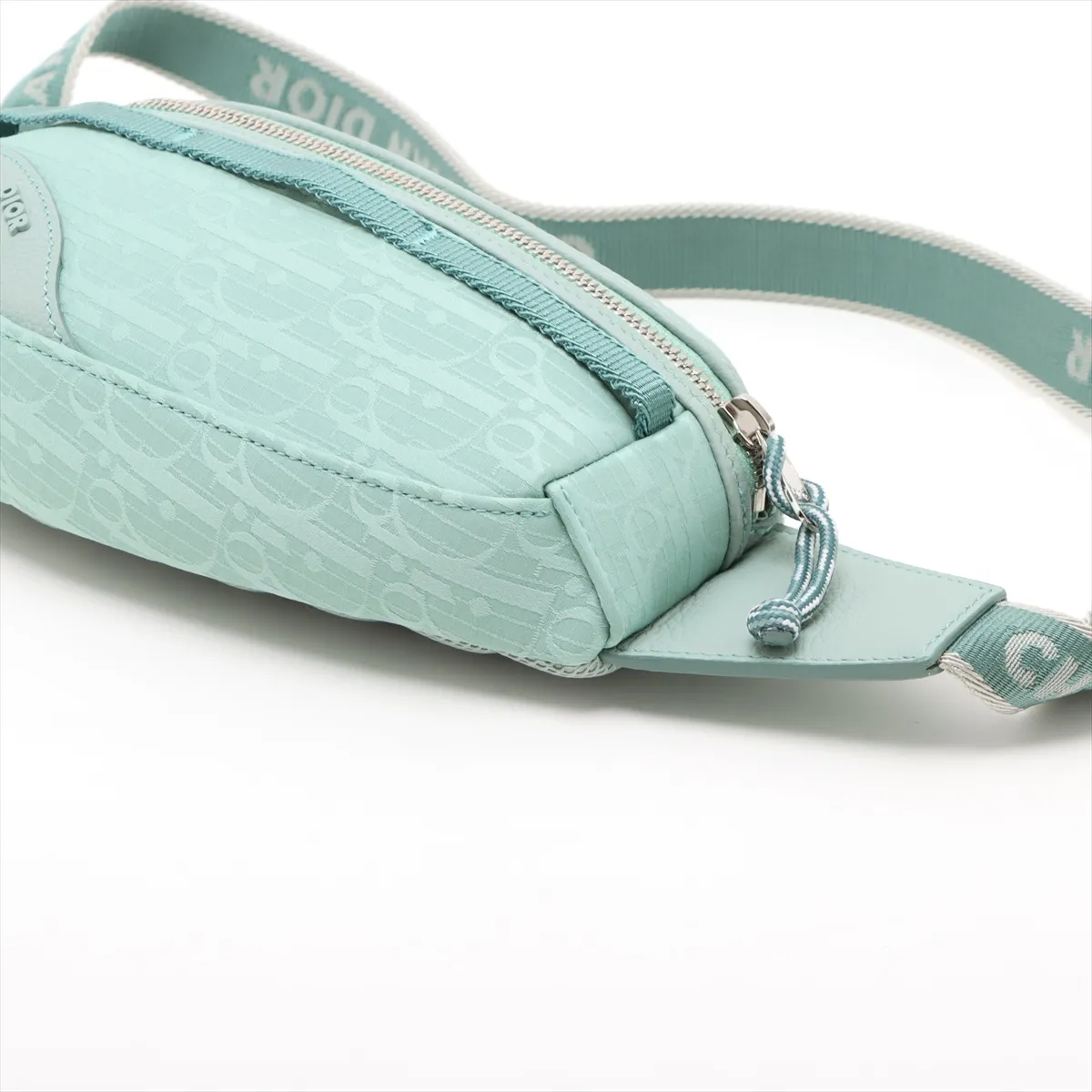 Green patterned nylon body bag with dark leather trim and a wide adjustable strap.