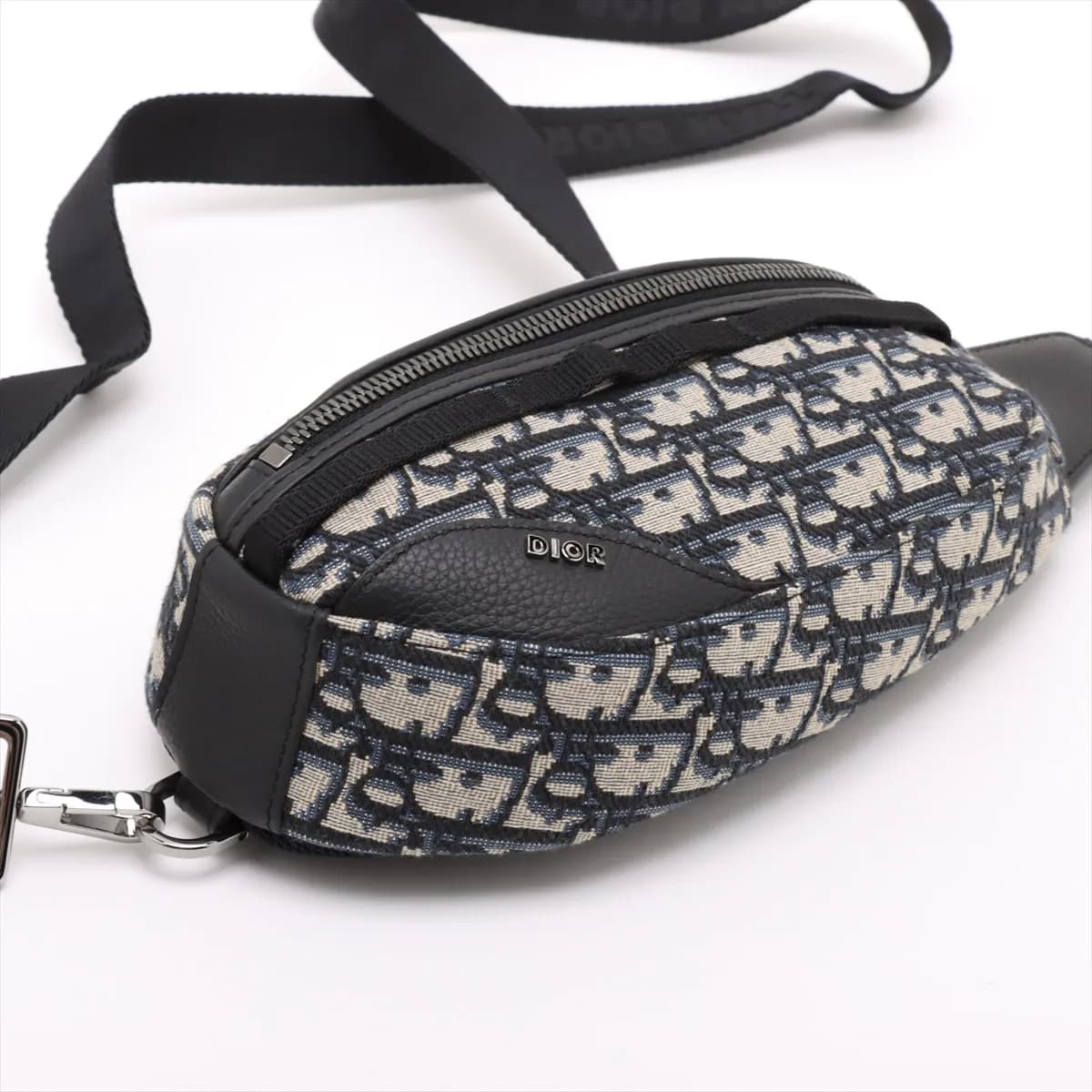 Navy jacquard-patterned canvas body bag with leather trim, buckle strap and front zip pocket