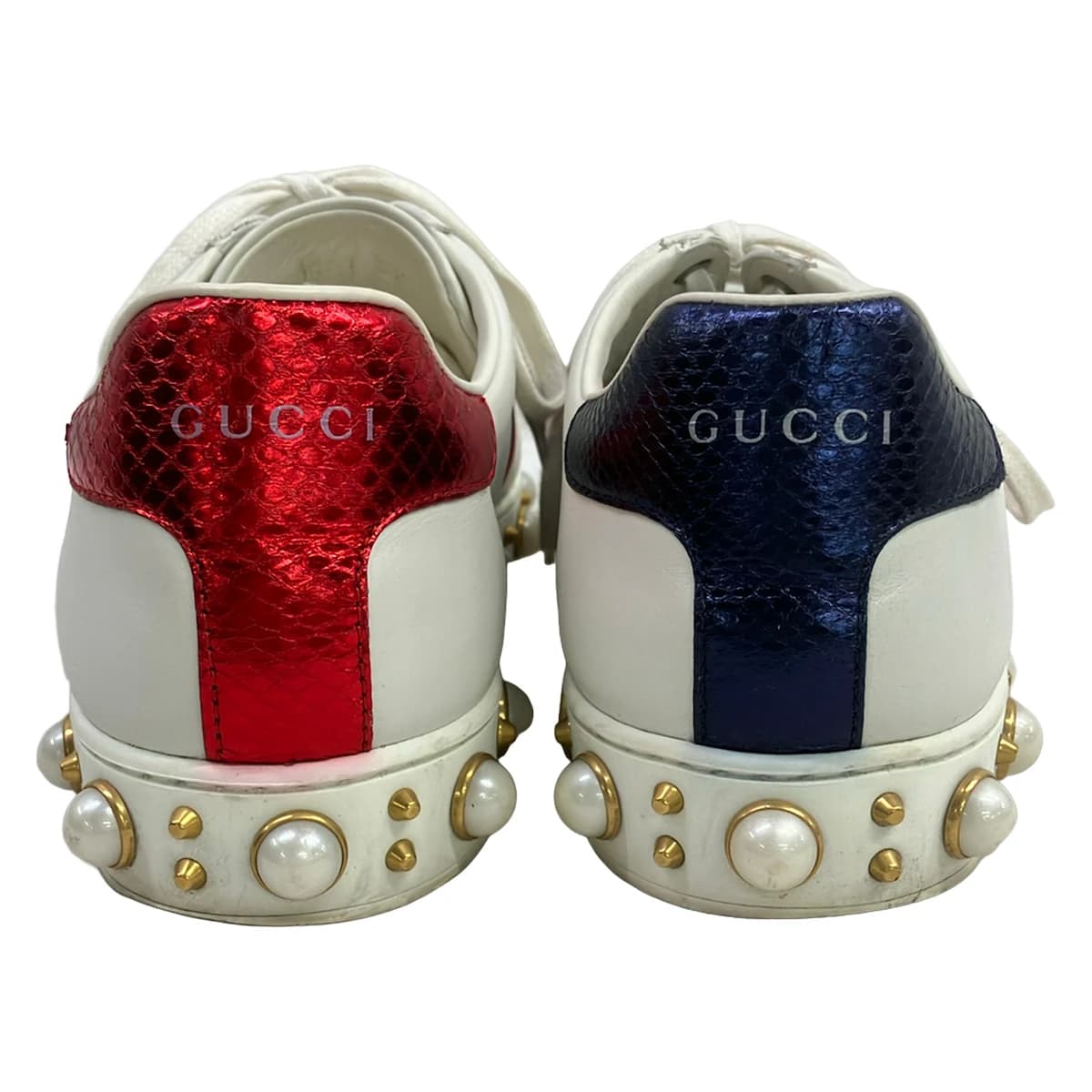Low-top sneakers in white with burgundy and navy side stripes.