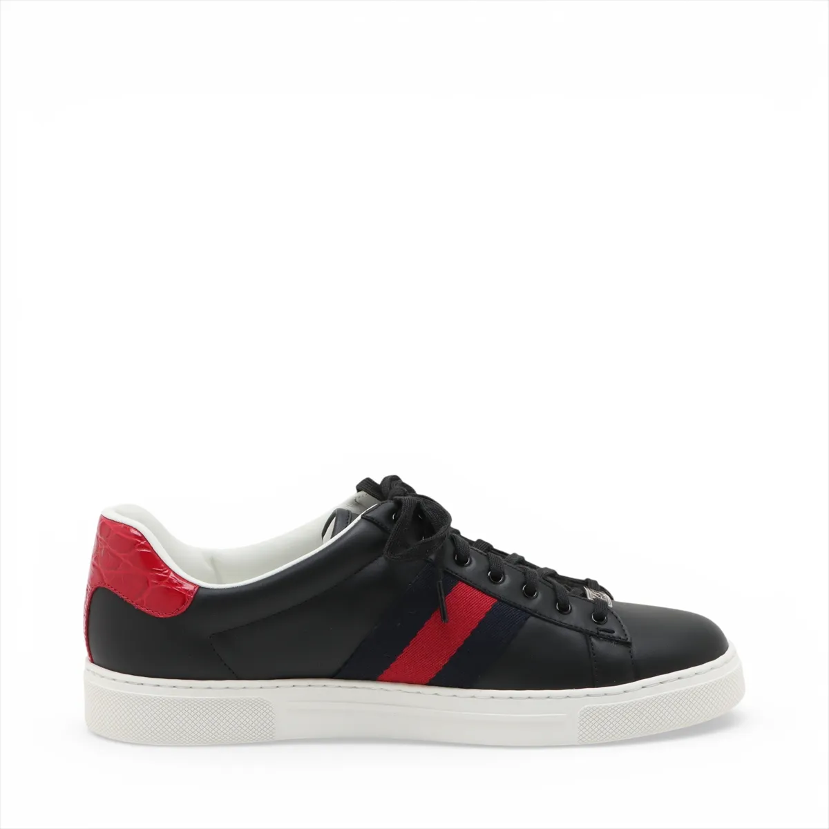 Black low-top sneakers with a thick white platform sole and a green and red stripe along the side.