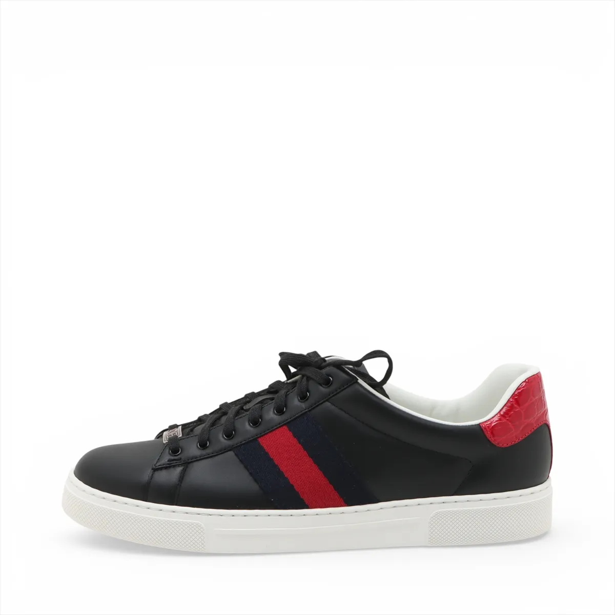 Black low-top sneakers with a thick white platform sole and a green and red stripe along the side.