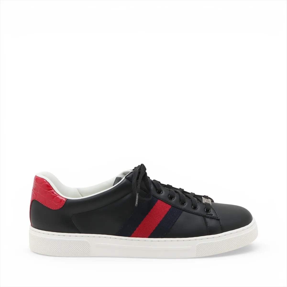 Black low-top sneakers with a thick white platform sole and a green and red stripe along the side.