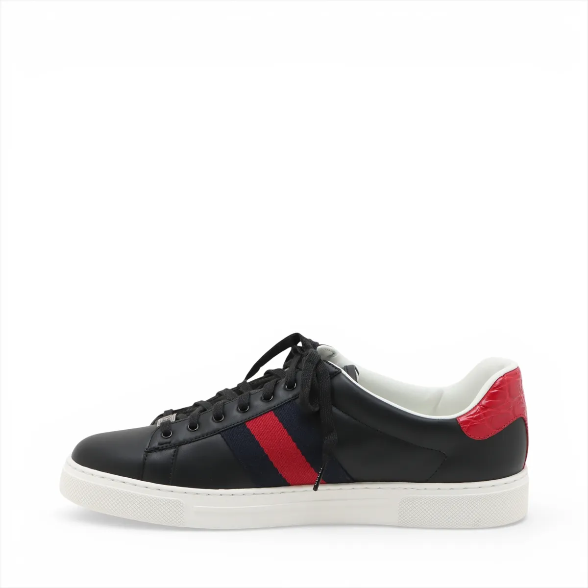 Black low-top sneakers with a thick white platform sole and a green and red stripe along the side.
