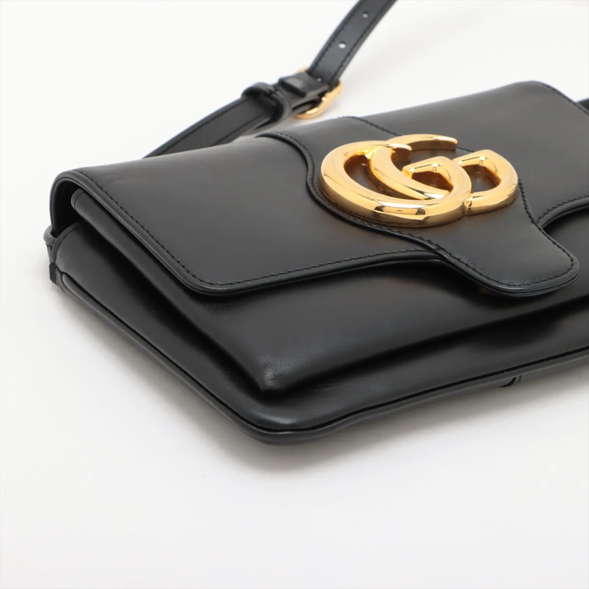 Product photograph of a small black leather bag with a shoulder strap.