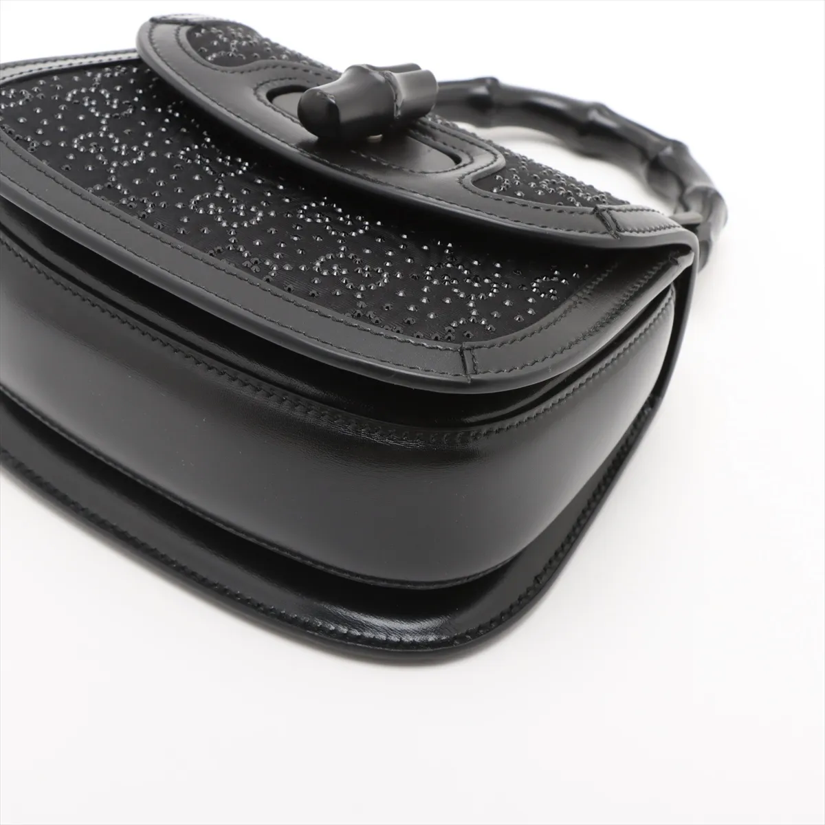 Small structured black handbag with a curved bamboo top handle and a jewelled clasp.