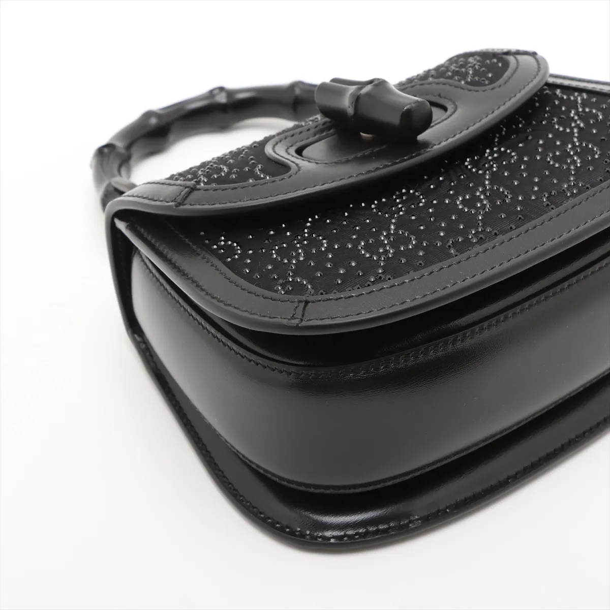 Small structured black handbag with a curved bamboo top handle and a jewelled clasp.