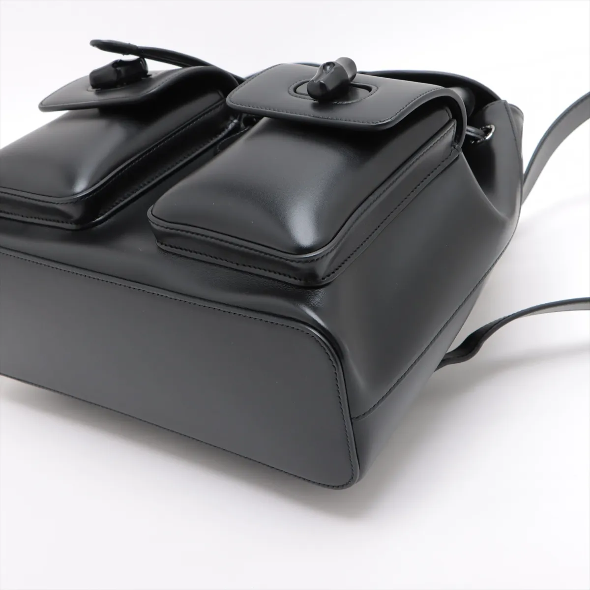 Product photograph of a black leather backpack with bamboo hardware.