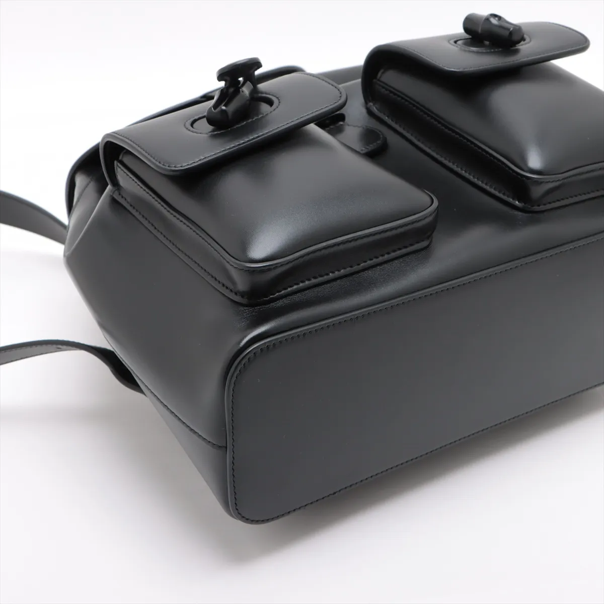 Product photograph of a black leather backpack with bamboo hardware.