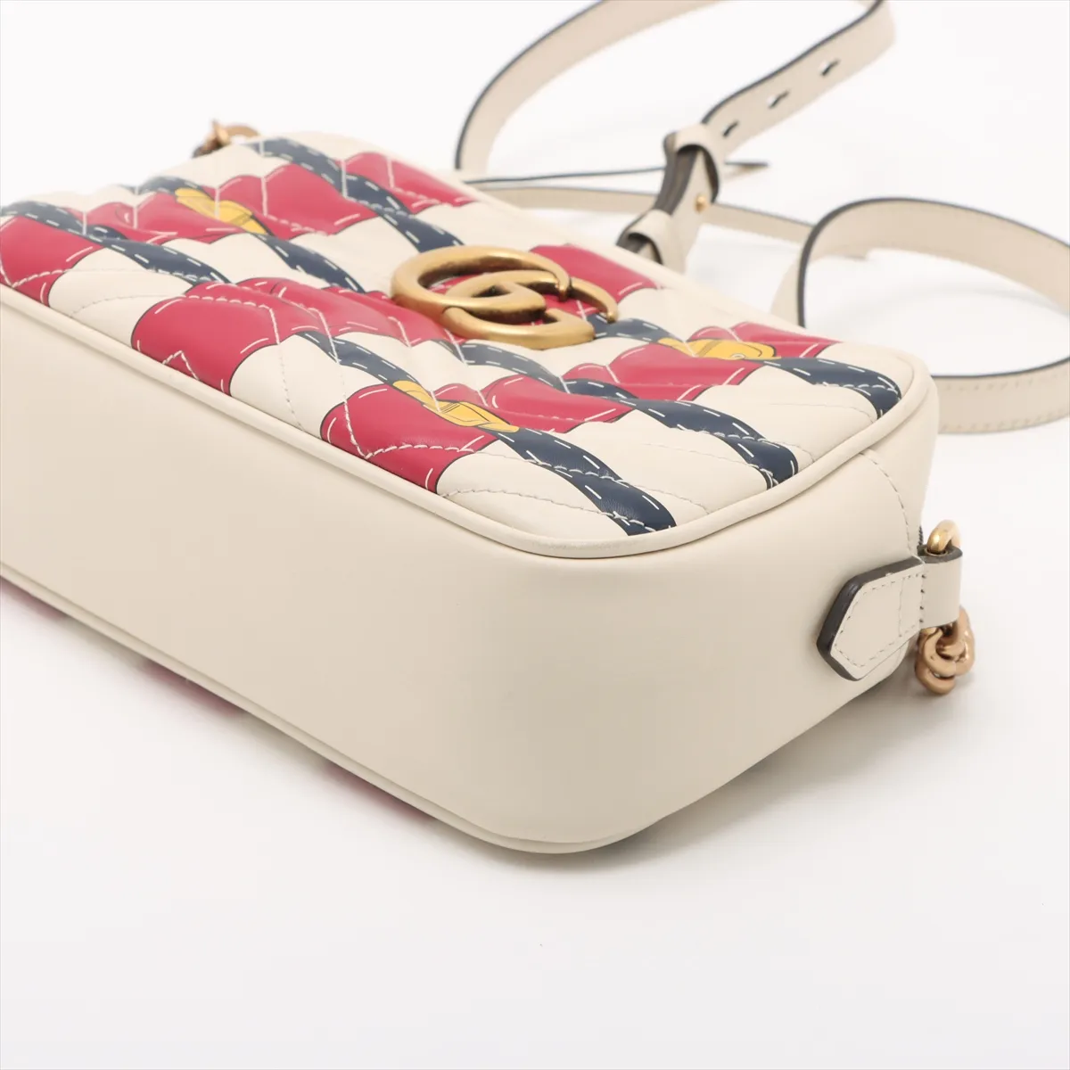 White quilted leather flap bag with red and blue trim and a gold-tone chain strap.