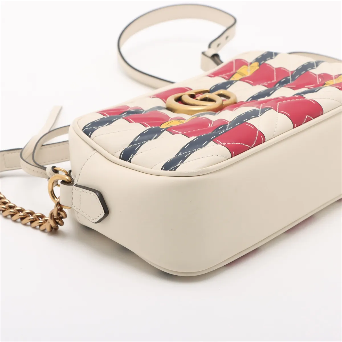White quilted leather flap bag with red and blue trim and a gold-tone chain strap.