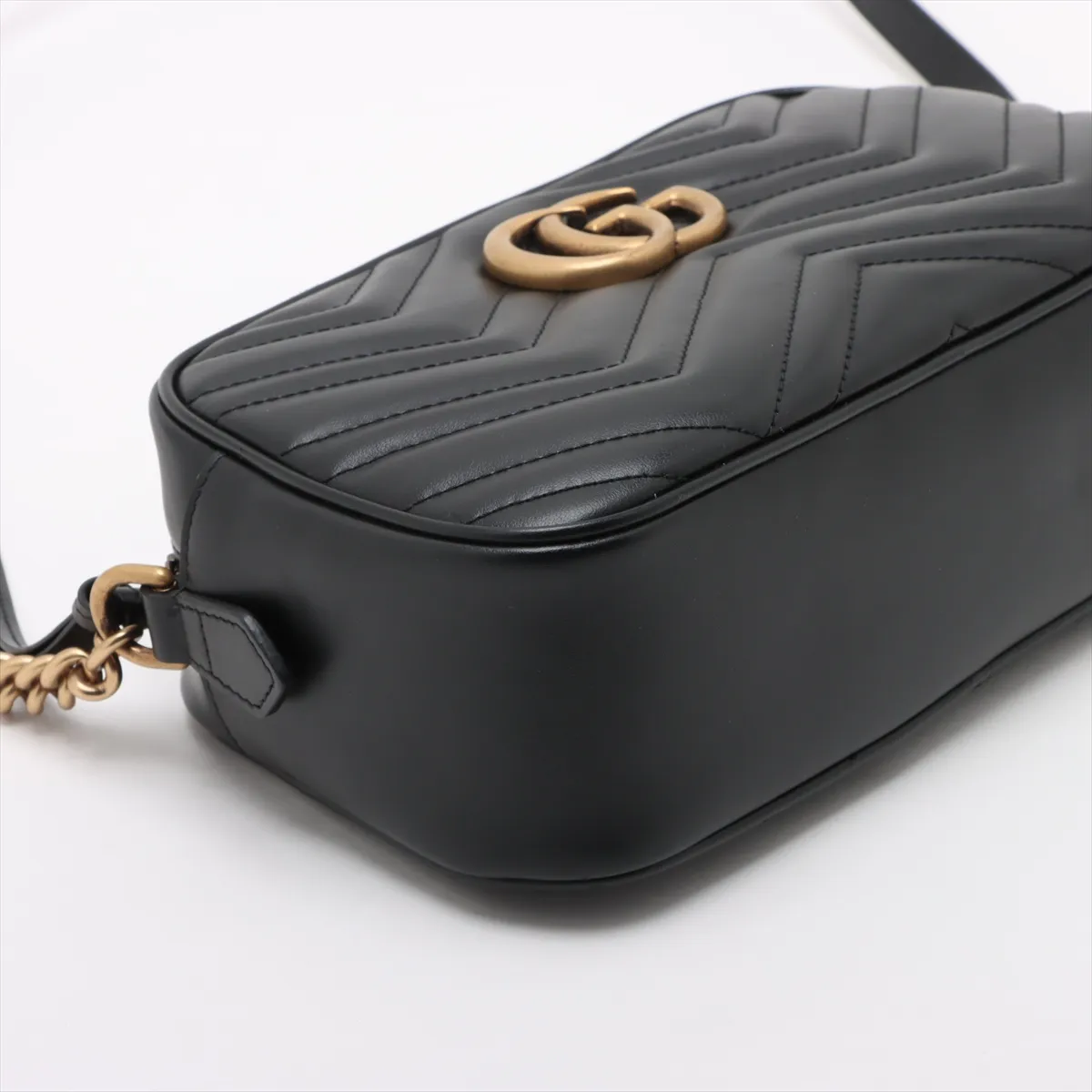 Quilted black leather shoulder bag with a chevron pattern, metal logo hardware and chain strap.