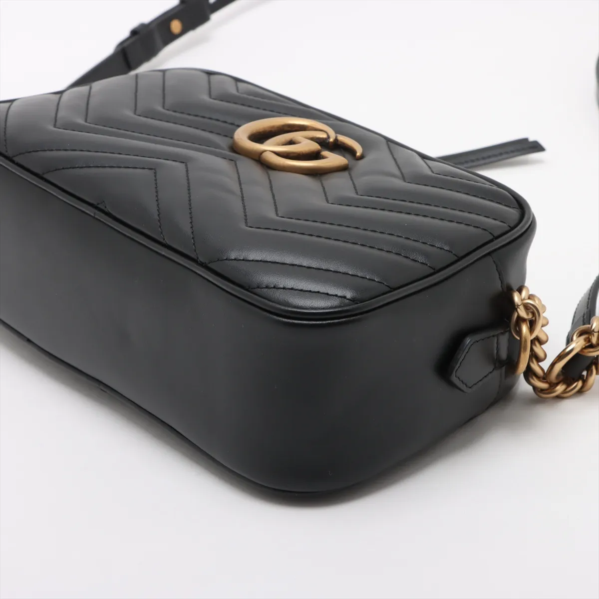 Quilted black leather shoulder bag with a chevron pattern, metal logo hardware and chain strap.