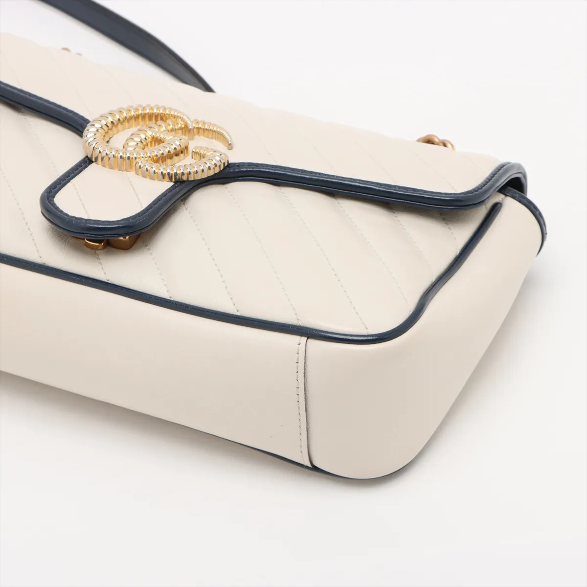 White chevron-quilted leather flap bag with navy trim, a double-G clasp and a chain strap.