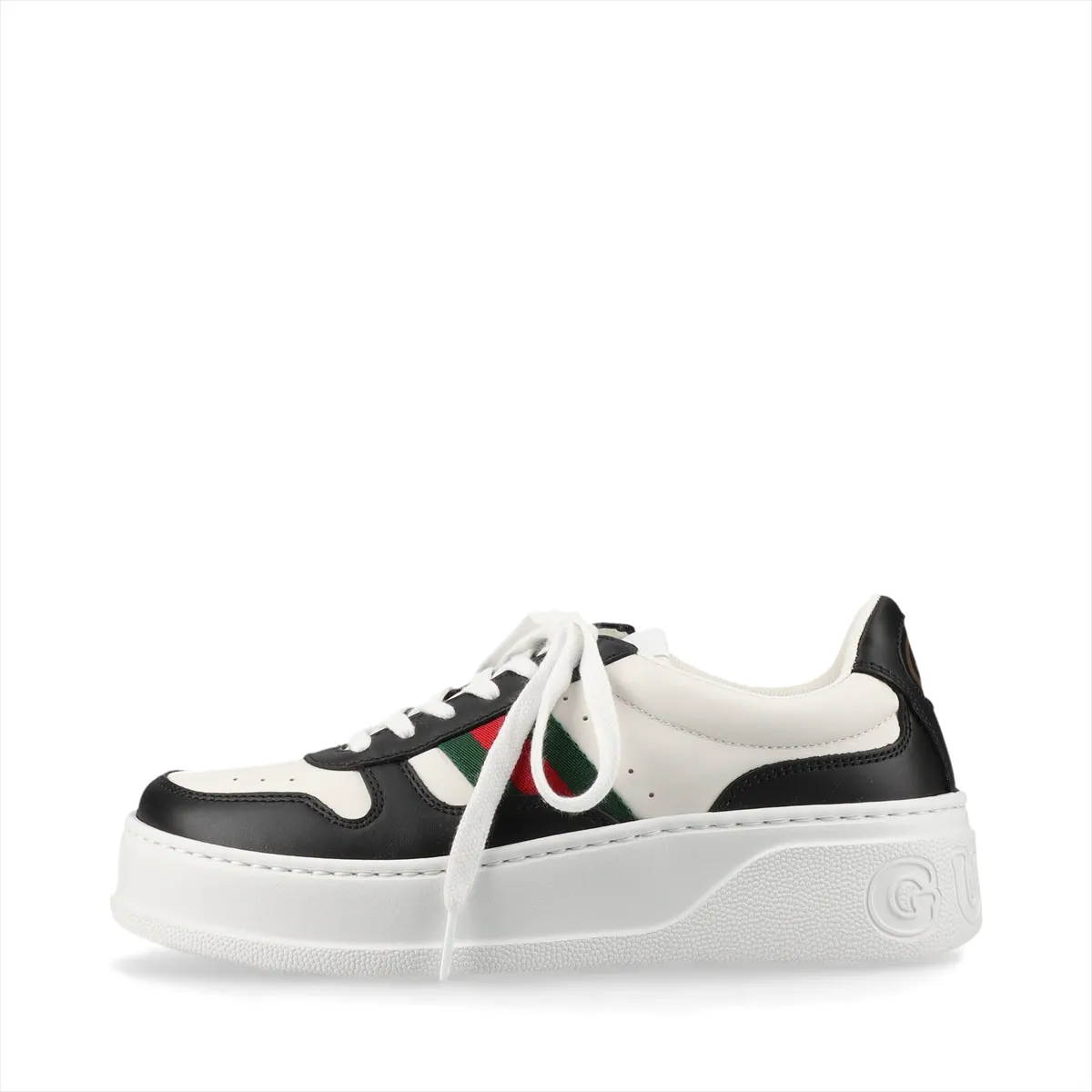 Platform low-top sneakers in black and white with a striped side band and metal logo detail.