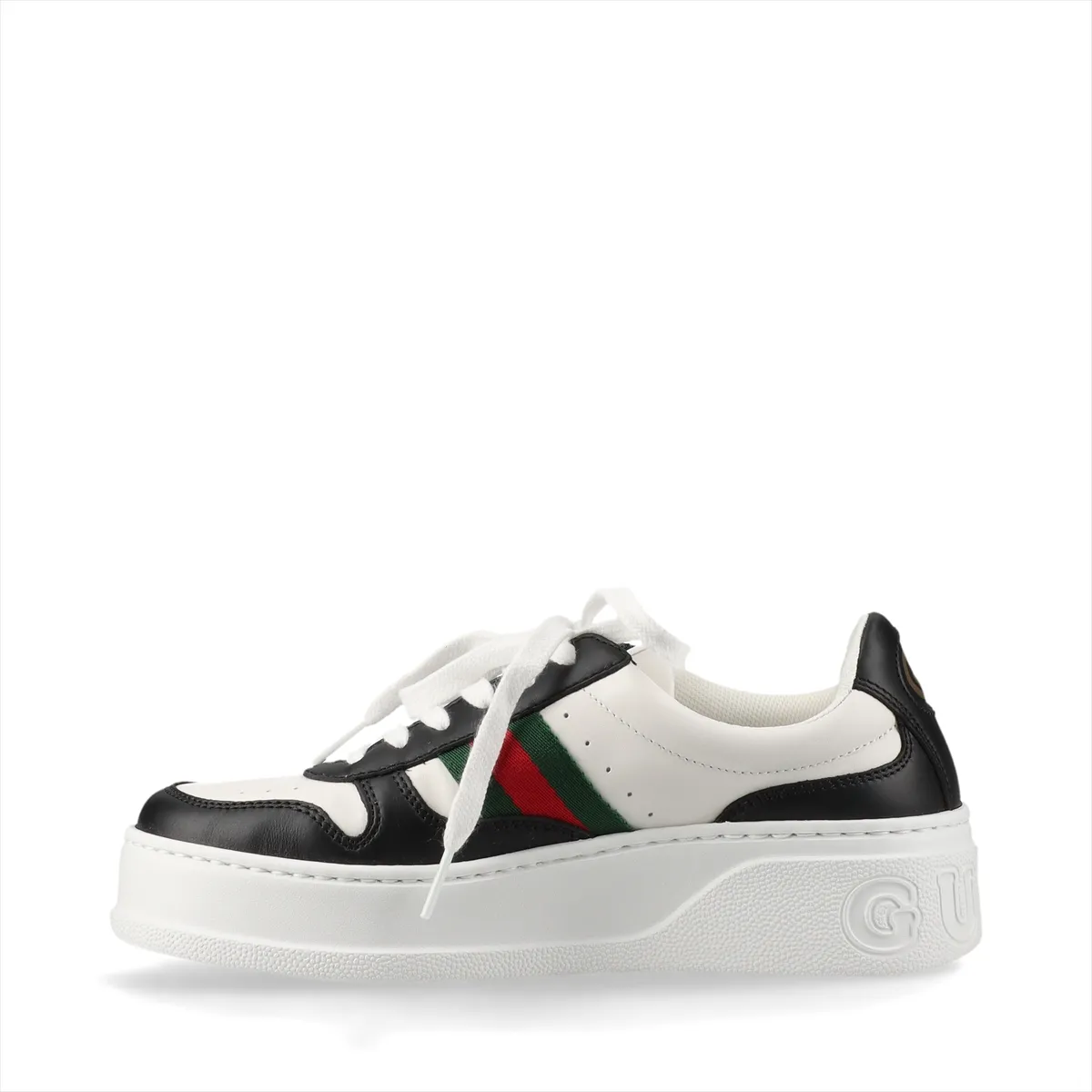 Platform low-top sneakers in black and white with a striped side band and metal logo detail.