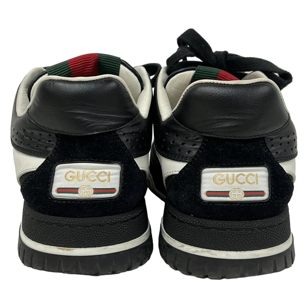 Black and white footwear with multicoloured striped web trim, side view