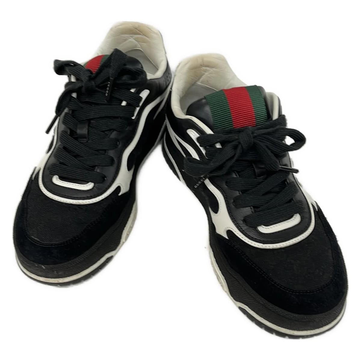 Black and white footwear with multicoloured striped web trim, side view