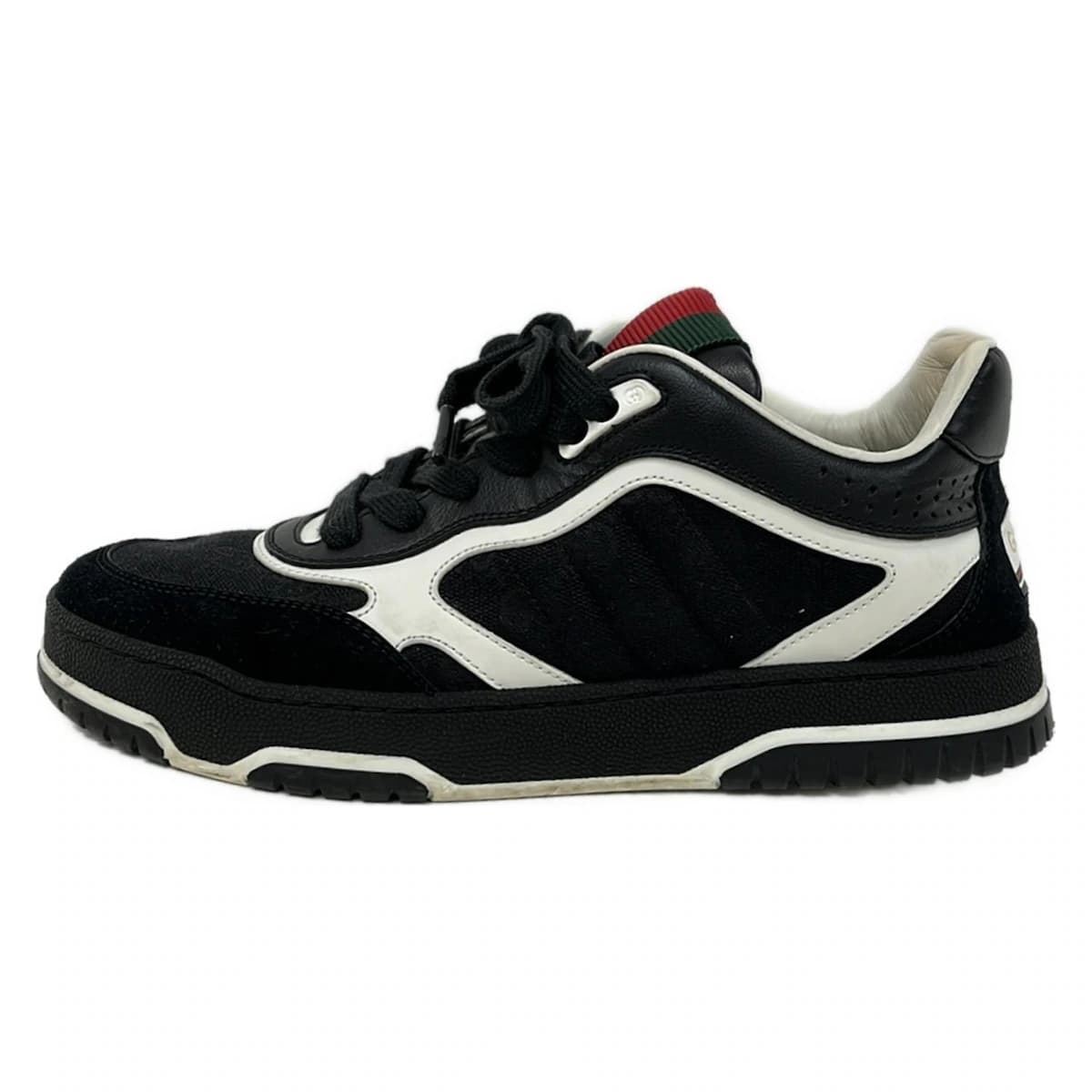 Black and white footwear with multicoloured striped web trim, side view