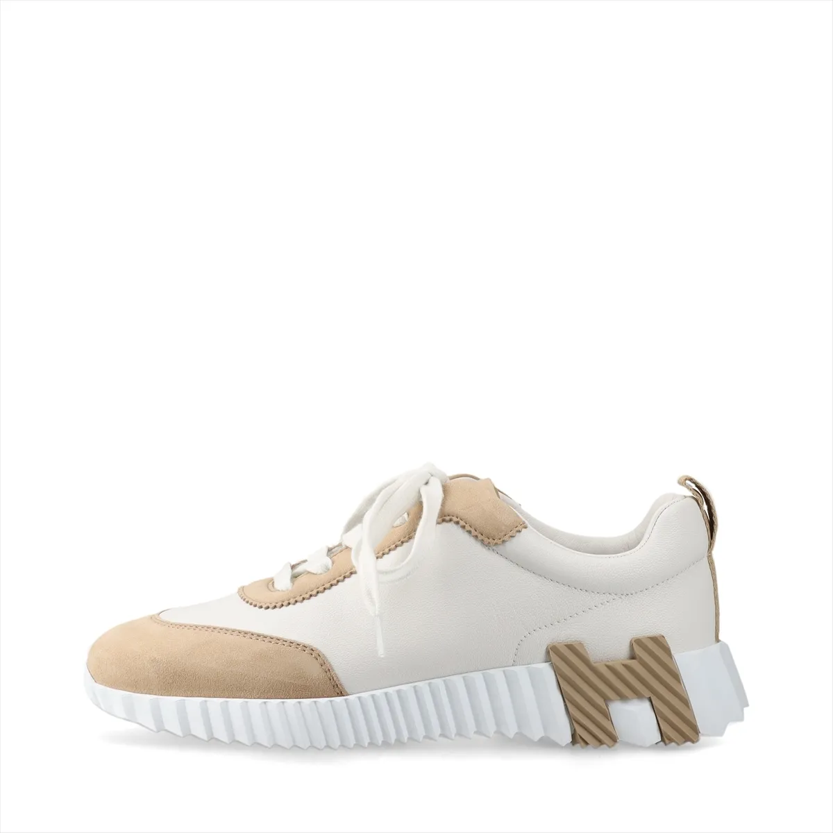 White and beige low-top sneakers in leather and suede with white laces and a chunky sole.