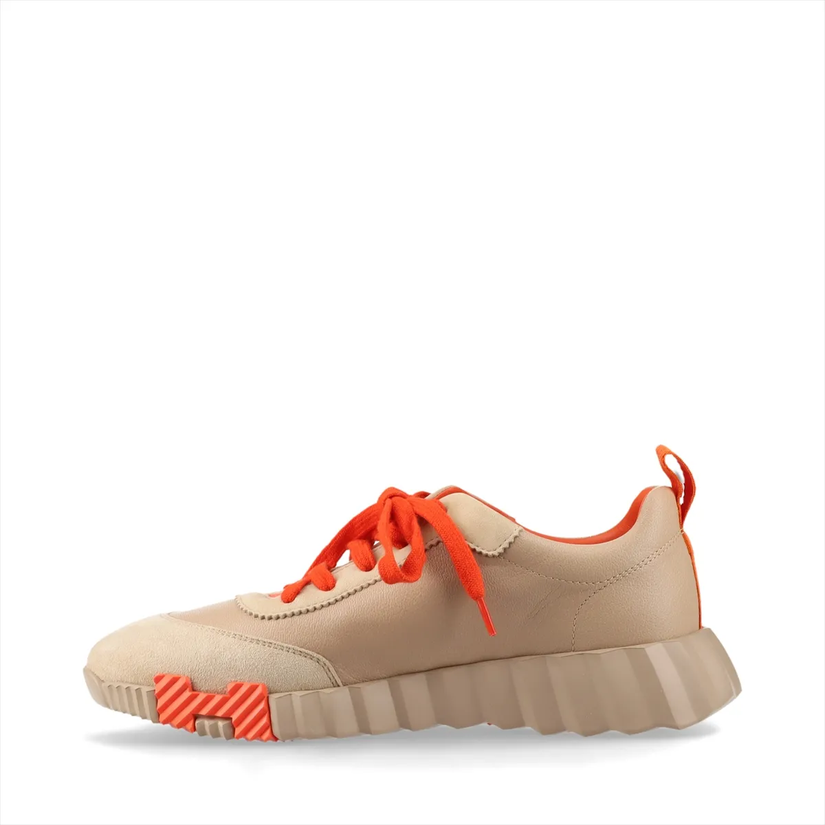 Low-top trainers in beige with orange accents, mixed smooth and napped panels, on a plain background.