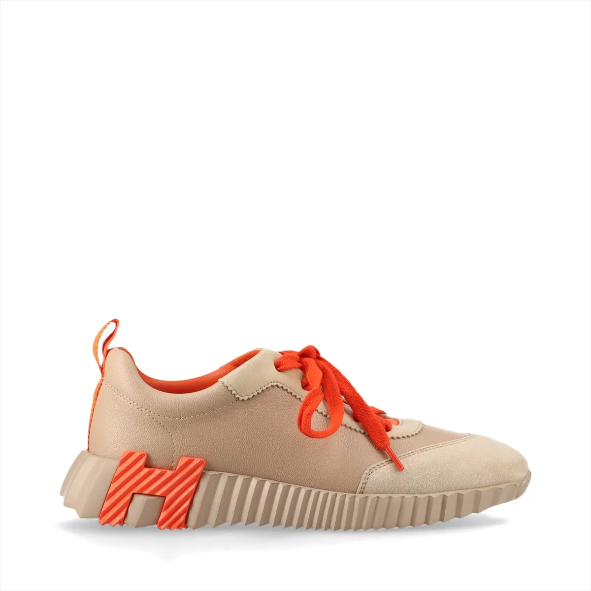 Low-top trainers in beige with orange accents, mixed smooth and napped panels, on a plain background.