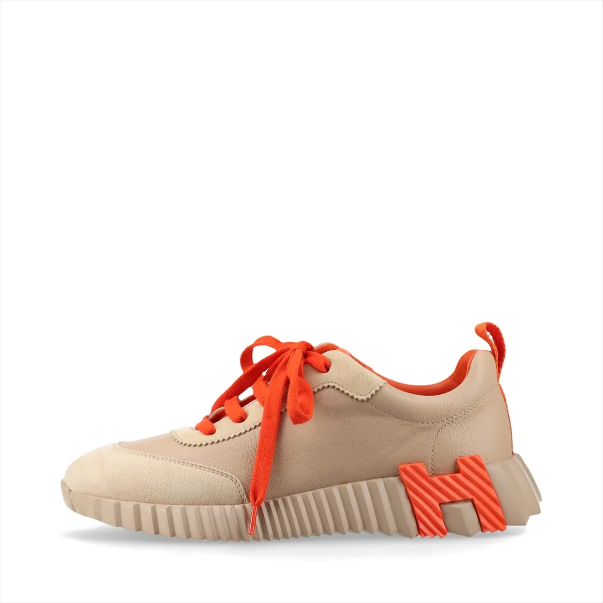 Low-top trainers in beige with orange accents, mixed smooth and napped panels, on a plain background.
