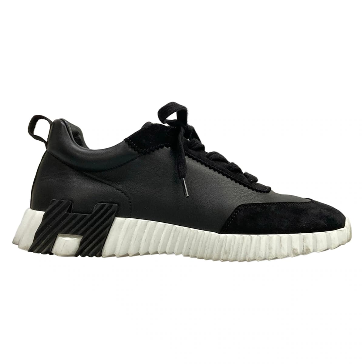 Pair of black low-top sneakers with a thick sole, shown side on.